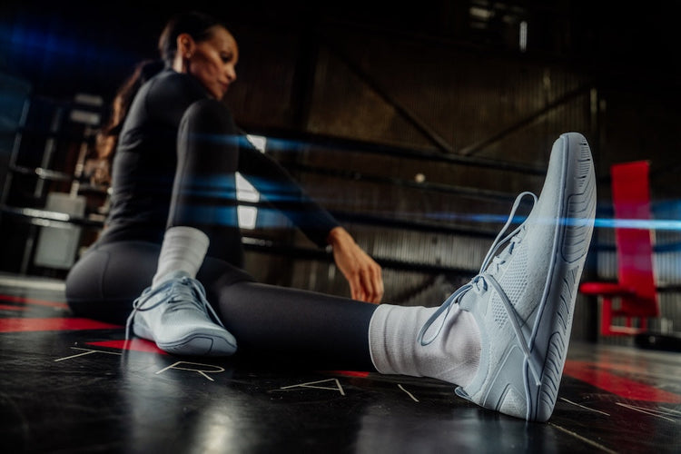 Woman wearing Xero Shoes stretching on the floor