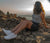 Woman laying on rocks wearing Xero Shoes in Italy enjoying a high up view